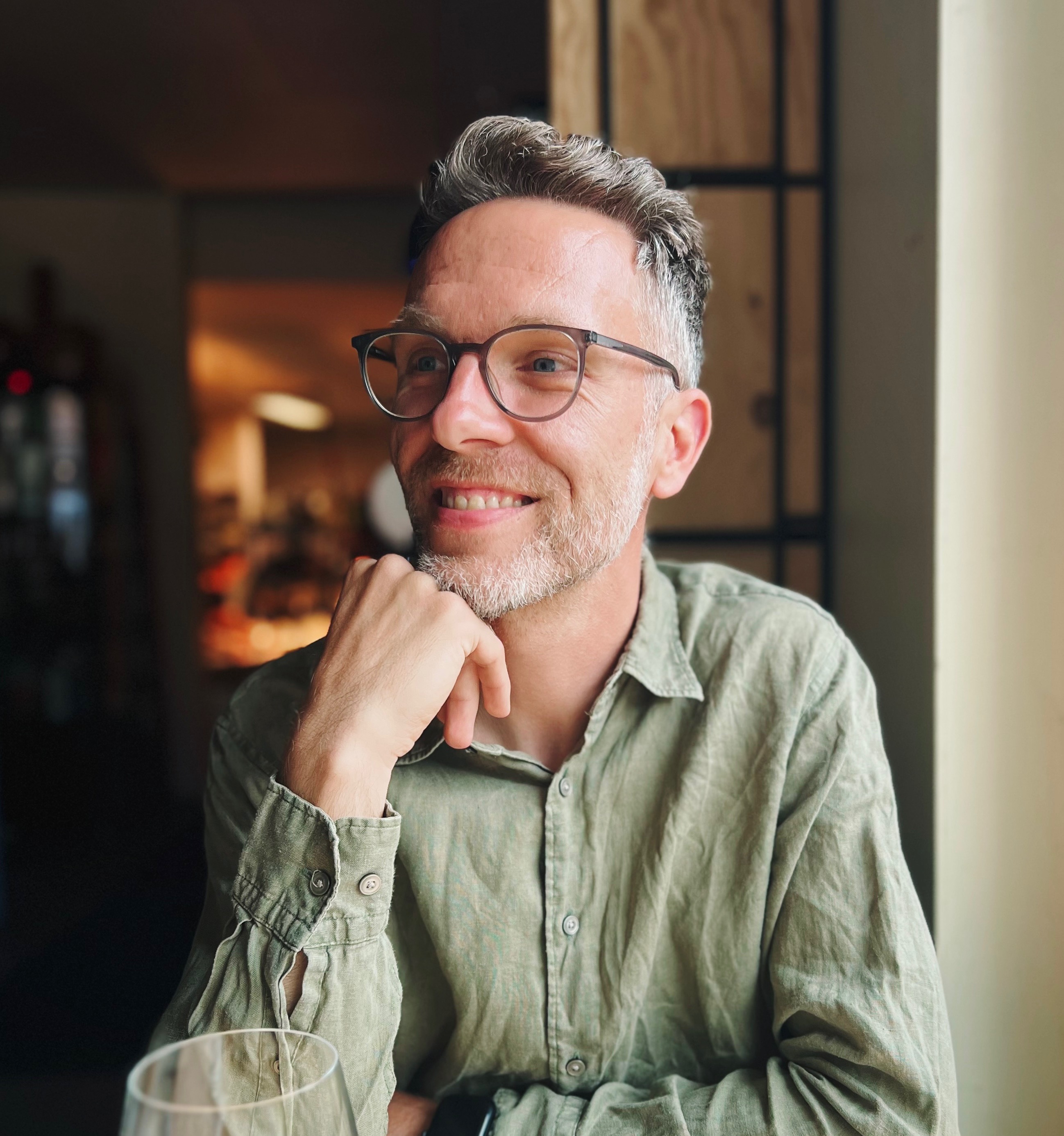 A smiling man with glasses and short hair, wearing a green shirt.